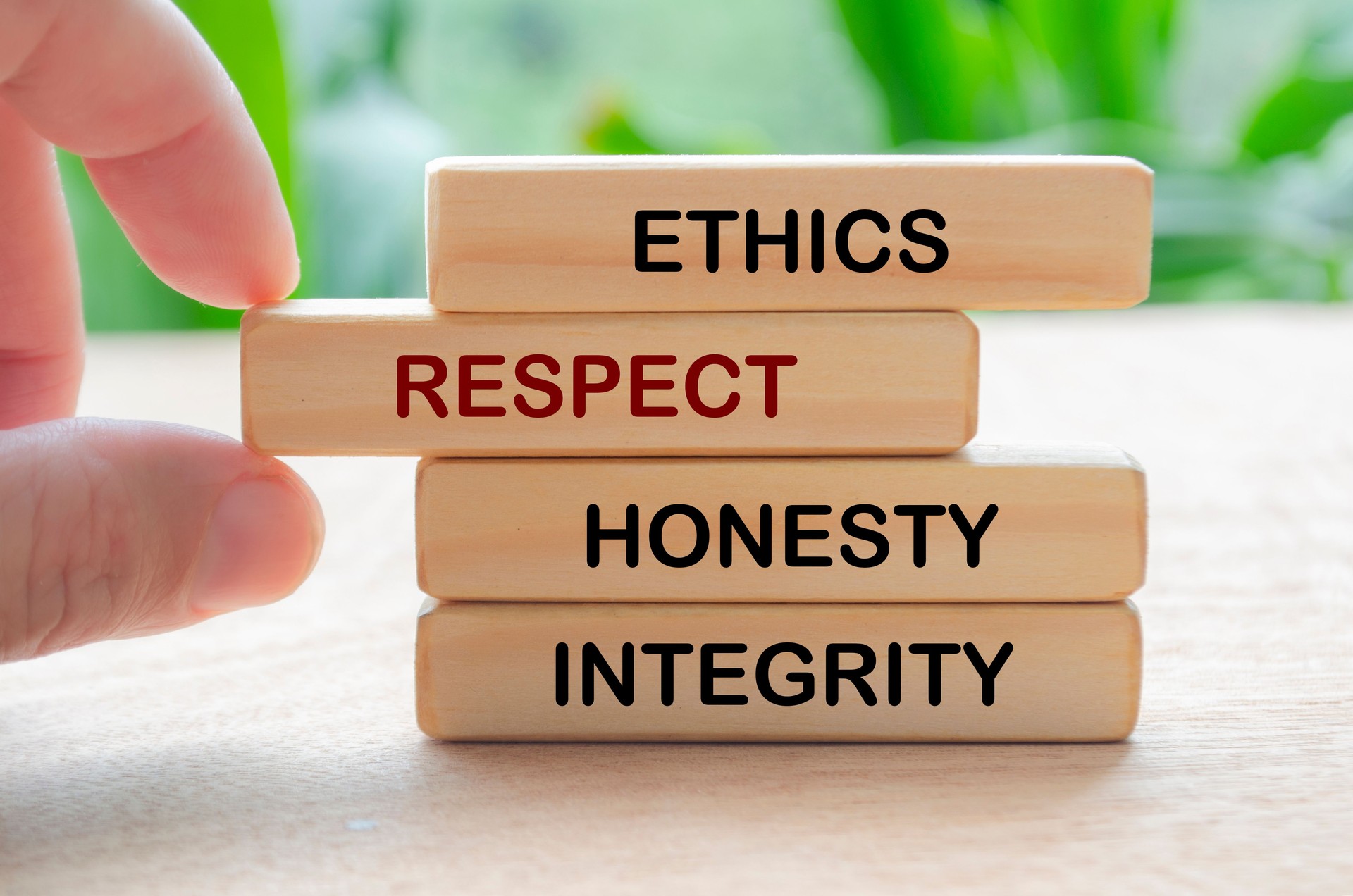 Ethics, respect, honesty and integrity text on wooden blocks with blurred nature background